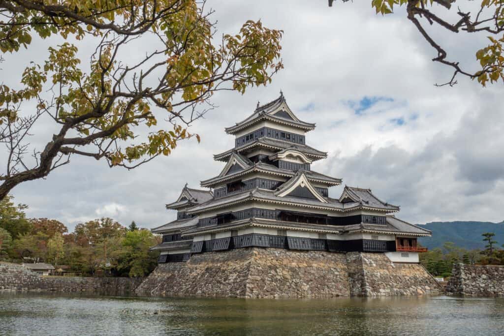 The Matsumoto castle in Matsumoto, Japan with its formidable black exterior which sits powerfully atop a plain known as a hirajiro. 