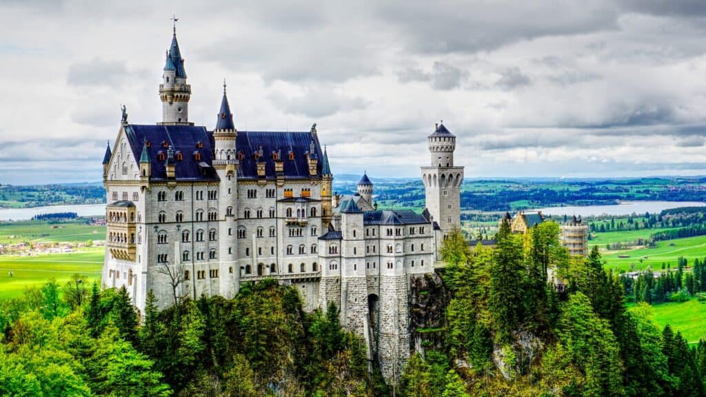 The beautiful, fairytale, Disney-like Neuschwanstein castle sits amidst stunning green landscape.