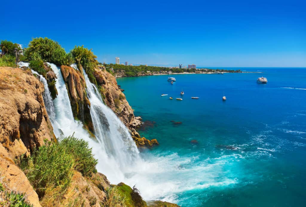 Streaming waterfall cascading off rocks to the calm, blue water below found in Turkey.